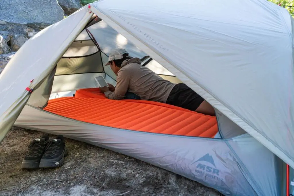 MSR Hubba Hubba LT2 – best backpacking tent for livability and rest. Camper relaxing inside the MSR Hubba Hubba, one of the best backpacking tents for comfort.