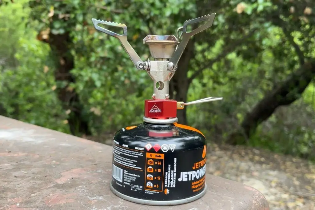 msr-pocket-rocket-2-stove MSR PocketRocket 2 backpacking stove mounted on a fuel canister in a wooded campsite.