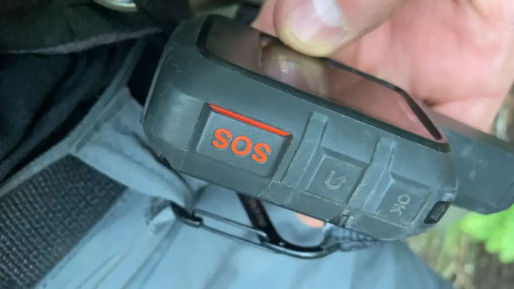 sos-button-garmin-inreach-mini-satellite-device Close-up of the orange SOS button on a Garmin inReach Mini satellite communicator, held in hand and clipped to a belt loop.