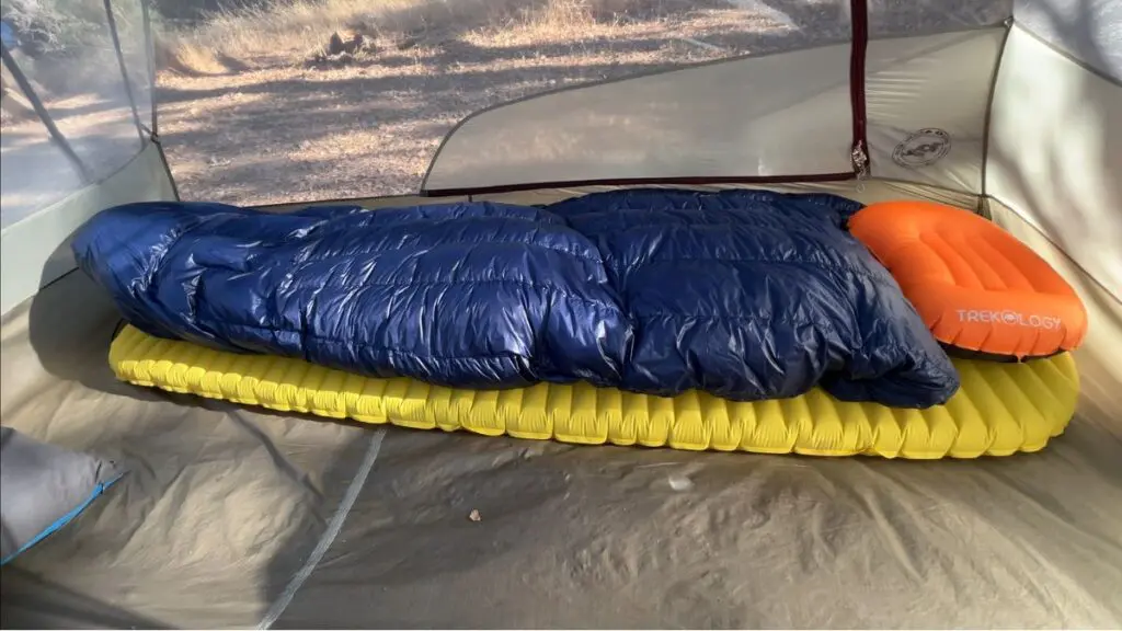 ultralight-backpacking-quilt-sleep-pad Navy down backpacking quilt on a yellow inflatable sleeping pad with an orange camp pillow, inside a backpacking tent.