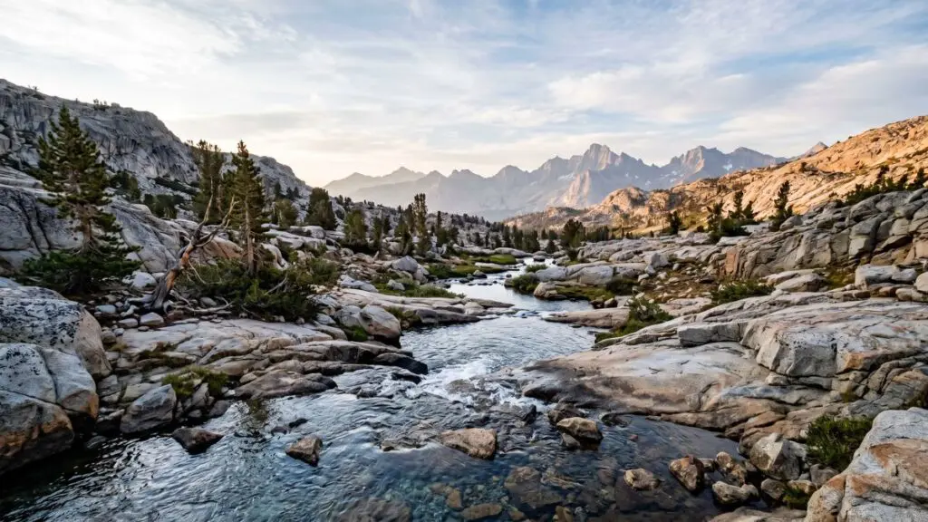 high-sierra-stream-water-collection Alpine stream flowing over granite through a High Sierra basin toward distant peaks at dusk — a typical backcountry refill source for a hydration bladder