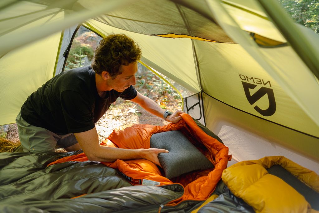 backpacking-pillows-guide Backpacker setting up a sleeping bag and pillow inside a backpacking tent